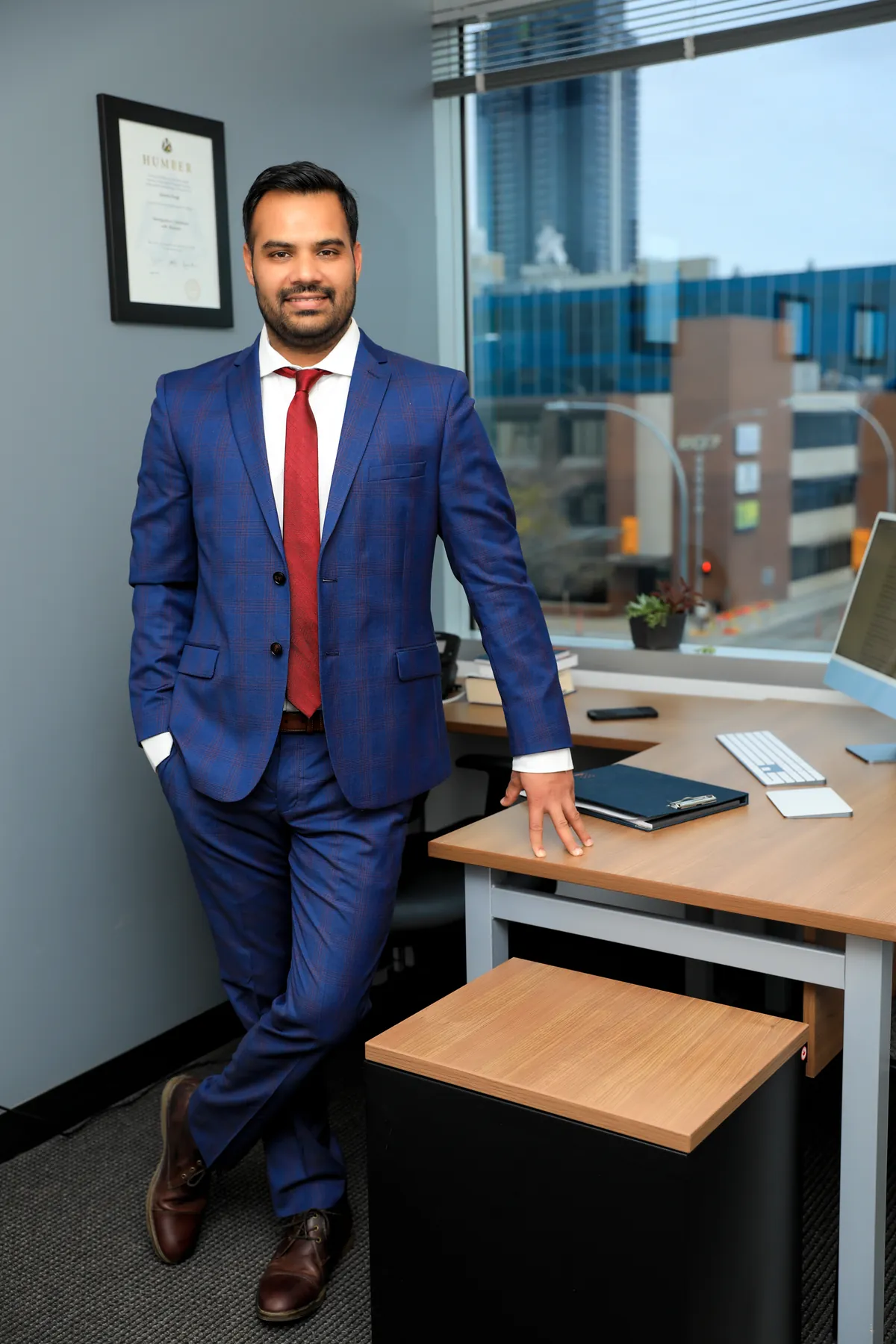 Jatinder Singh, RCIC, at the Verge Immigration office in front of his Humber immigration credential